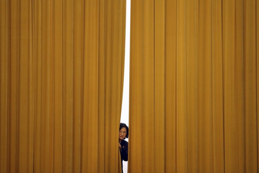 A woman peeps out from behind a curtain ahead of a press conference following a plenary session of China’s National People’s Congress, at the Great Hall of the People in Beijing on March 19. Most people in Western economies know very little of the purposes behind Chinese politics or the meetings of the legislature. Photo: AP