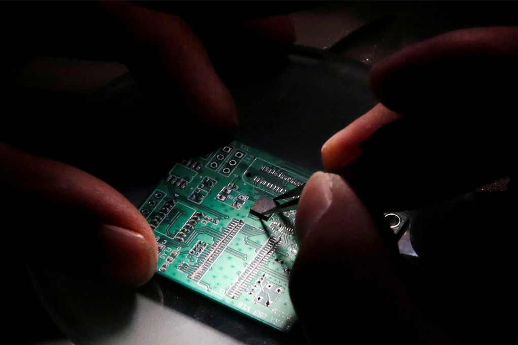 A researcher plants a semiconductor on an interface board which is placed under a microscope during a research work to design and develop a semiconductor product at Tsinghua Unigroup research centre in Beijing. Photo: Reuters