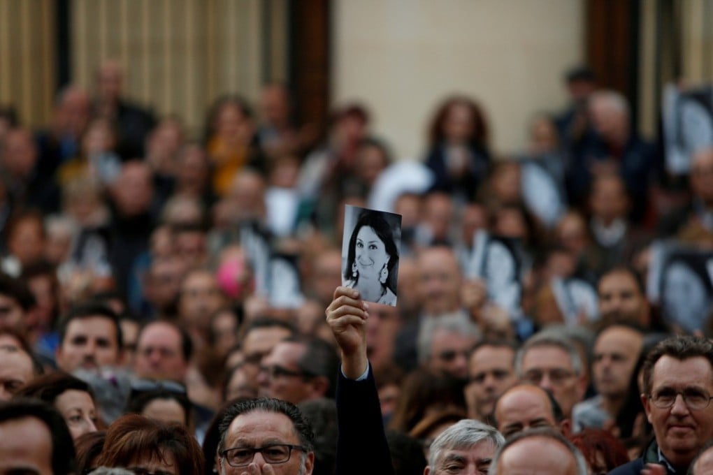 A man holds up a photo of assassinated anti-corruption journalist Daphne Caruana Galizia during a vigil and demonstration, marking six months since her murder in a car bomb, in Valletta, Malta April 16, 2018. Photo: Reuters