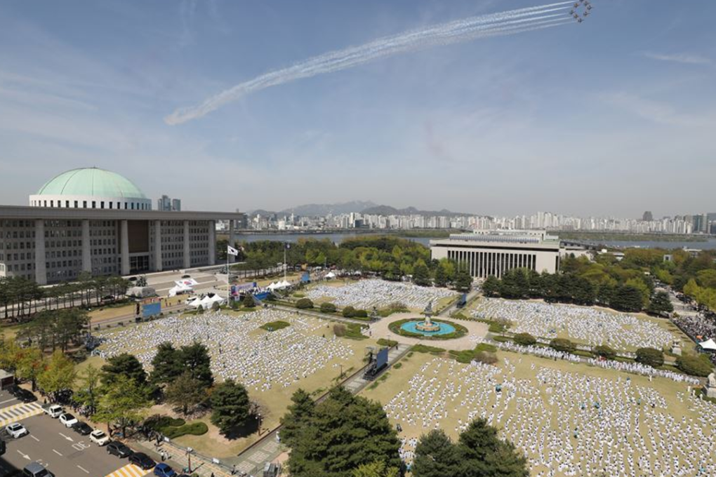 About 8,800 taekwondo martial artists perform poomsae in front of the National Assembly in Yeouido, Seoul. Jets from the South Korean air force's 53rd Air Demonstration Group fly above. Photo: Yonhap