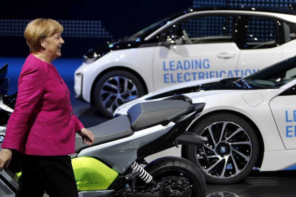 German Chancellor Angela Merkel walks past electricity-powered vehicles at the booth of the German car manufacturer BMW during her visit to the Frankfurt Auto Show in September 2017.  Recent indicators show that German manufacturing growth is slowing in 2018. Photo: AP