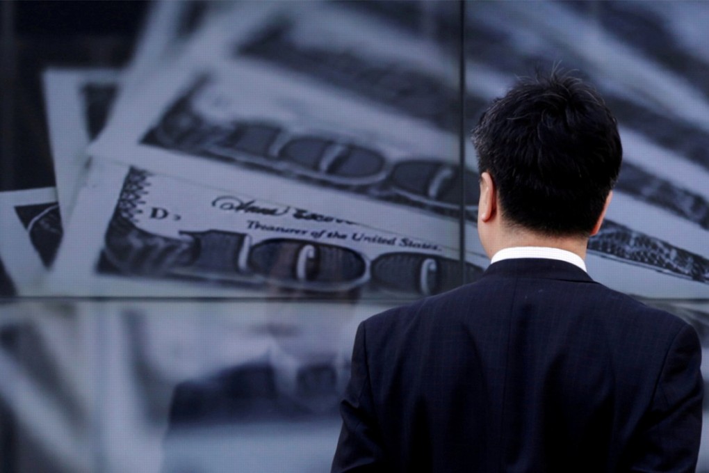 A businessman looks at a screen displaying a photo of US dollar bank notes in Tokyo in 2013. Japanese banks have steadily expanded their US dollar loan books. Photo: Reuters