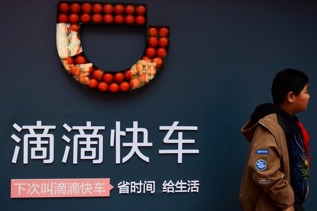 A boy walks past a sign of ride-hailing company Didi Chuxing in Shenyang, Liaoning province. Photo: Reuters