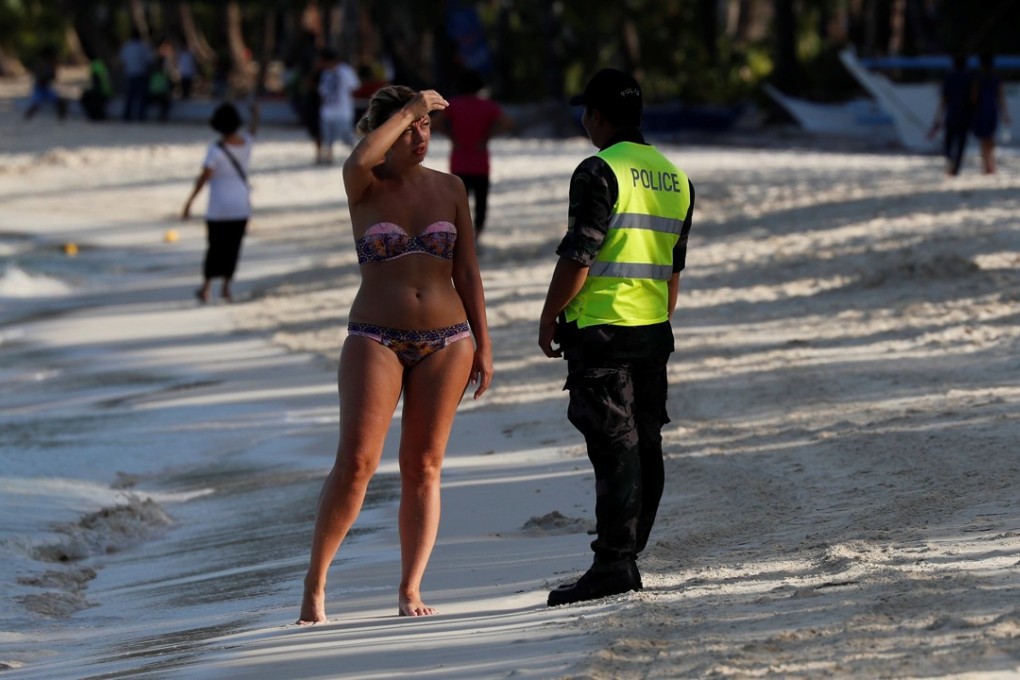 A policeman asks a tourist to leave the beach during the shutdown of the holiday island Boracay. Photo: Reuters