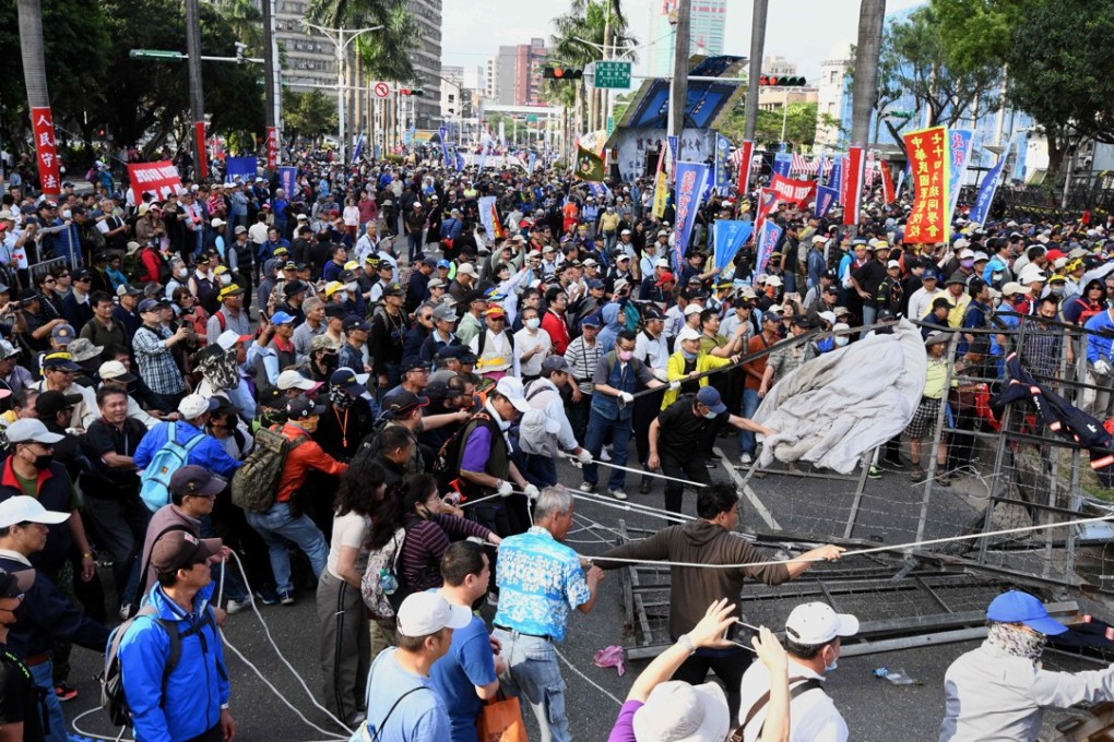 Anti-pension reform protesters pull down barricades at the entrance to parliament during a demonstration in Taipei on Wednesday. Photo: Agence France-Presse