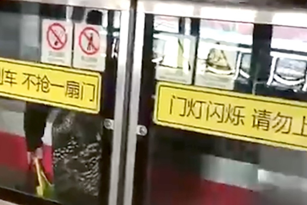 The woman stuck behind the safety barrier as a train pulls away. Photo: Sina.com