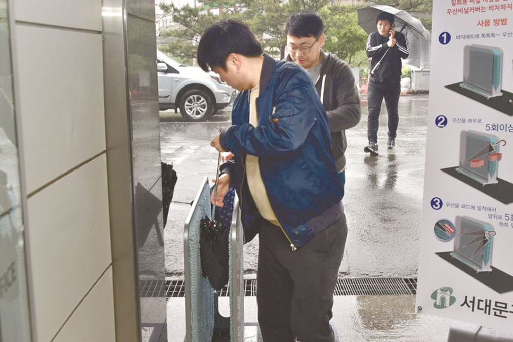 A man uses a dryer to remove rainwater from his umbrella in front of Seoul City Hall. Photo: Yonhap