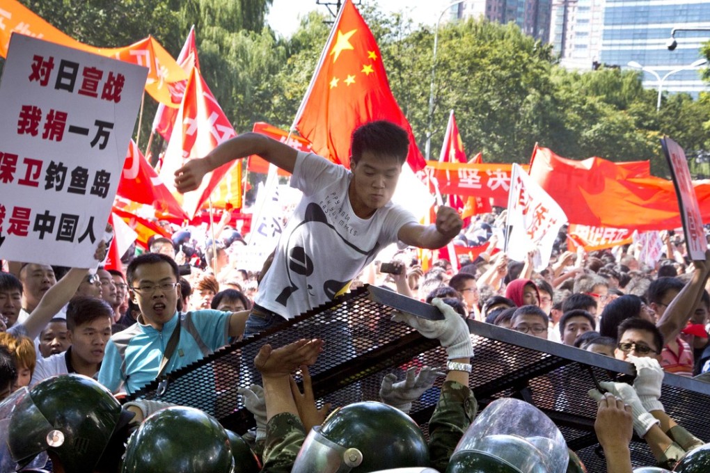 A demonstrator kicks the fence set up by paramilitary policemen as a protest outside the Japanese embassy in Beijing turns violent, on September 15, 2012. Angry anti-Japanese demonstrations took place in cities across China on the day over Japan’s control of the disputed Diaoyu/Senkaku islands. Photo: AP