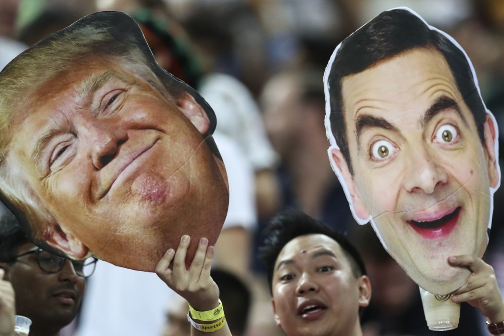 A fan holds up cutouts of US President Donald Trump and Mr Bean, played by British actor Rowan Atkinson, during the HSBC World Rugby Sevens Series 2018 finals on April 29 in Singapore. Trump’s “madman” diplomacy might just secure him enough foreign policy wins to shore up his reputation at home. Photo: AP