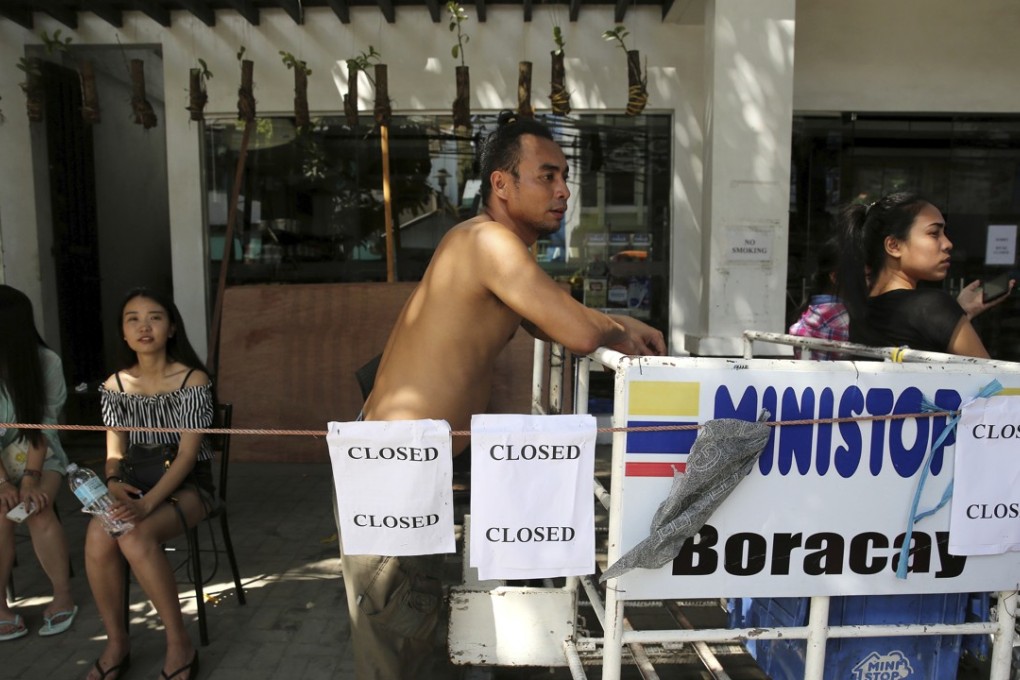 People wait outside a shop that ceased operations on Boracay on April 25, after Philippine President Rodrigo Duterte closed the island saying the waters off its beaches had become a "cesspool" due to overcrowding and development. Photo: AP
