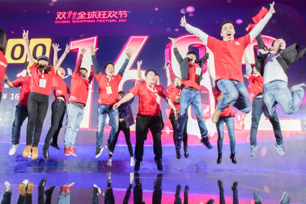 Staff pose for photos in front of a screen showing total sales at over 168 billion yuan soon after the end of the Singles’ Day shopping festival, at a gala event in Shanghai early on November 12, 2017. Photo: Agence France-Presse