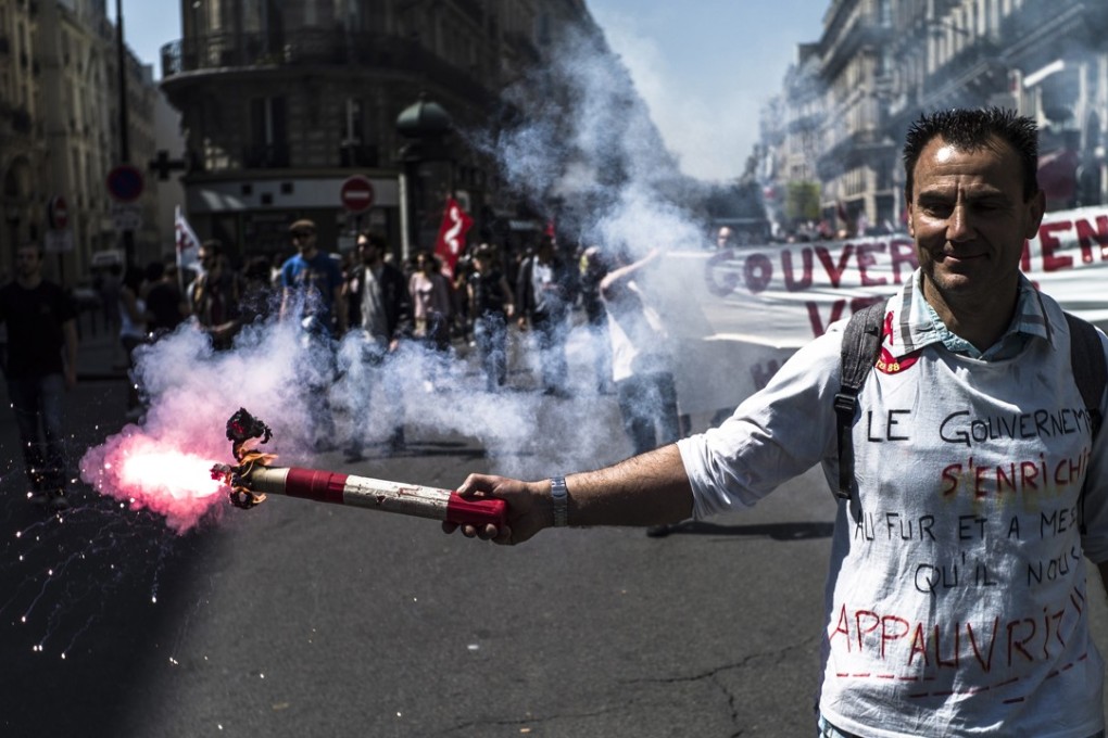 A protester lights a flare during a demonstration against the policies of French President Emmanuel Macron on Saturday. Photo: EPA-EFE