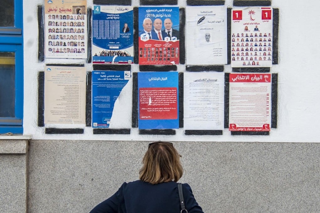 A woman reads electoral posters in Tunis, Tunisia. Photo: AP