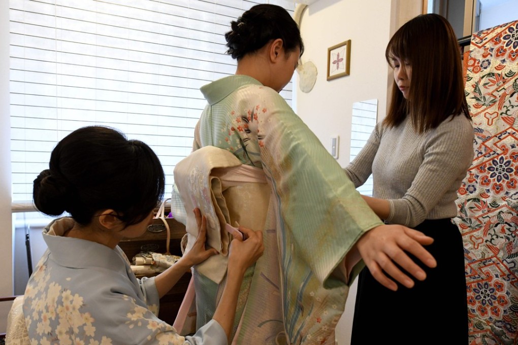 Kahori Ochi (left), owner of a kimono rental shop, fits a kimono to Dutch tourist Ruby Francisco at her shop in Tokyo. Photo: AFP