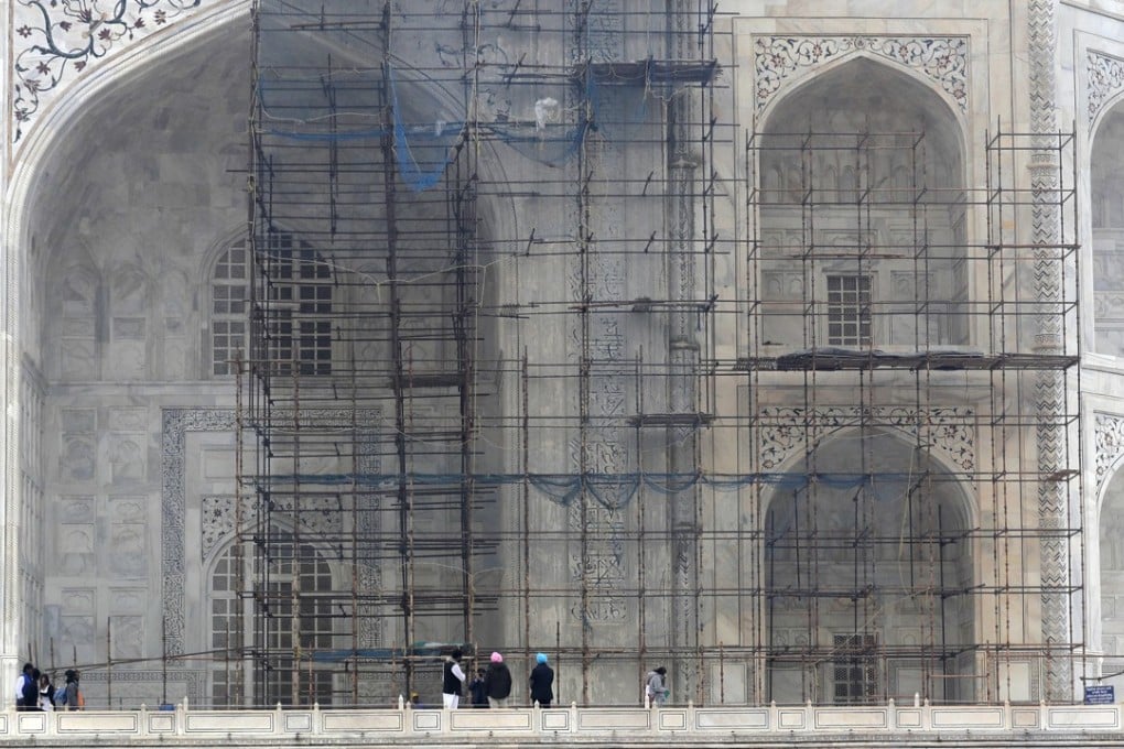 Tourists walk past a discoloured wall of the Taj Mahal caused by environmental pollution which stands out in contrast against one which has been cleaned in Agra, India. Photo: AP