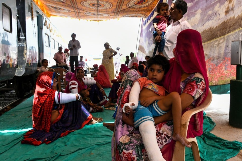 Patients and their relatives sit outside the Lifeline Express hospital train ahead of treatment in Jalore in India’s western state of Rajasthan. Photo: AFP