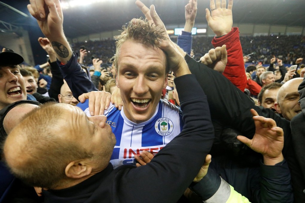 Wigan Athletic's Dan Burn celebrates with fans on the pitch after beating Manchester City in the 2018 FA Cup. Photo: Reuters