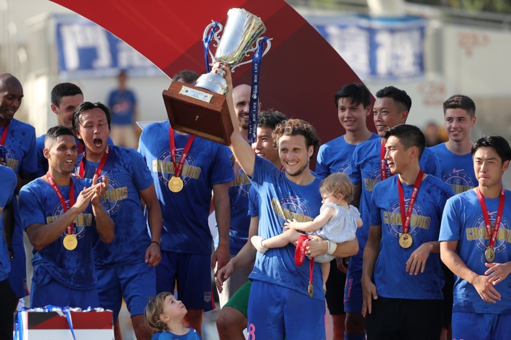 Diego Forlán lifts the Hong Kong Premier League trophy while he carries his infant daughter after Kitchee beat Yuen Long 2-0 at Mong Kok Stadium. Photos: Winson Wong