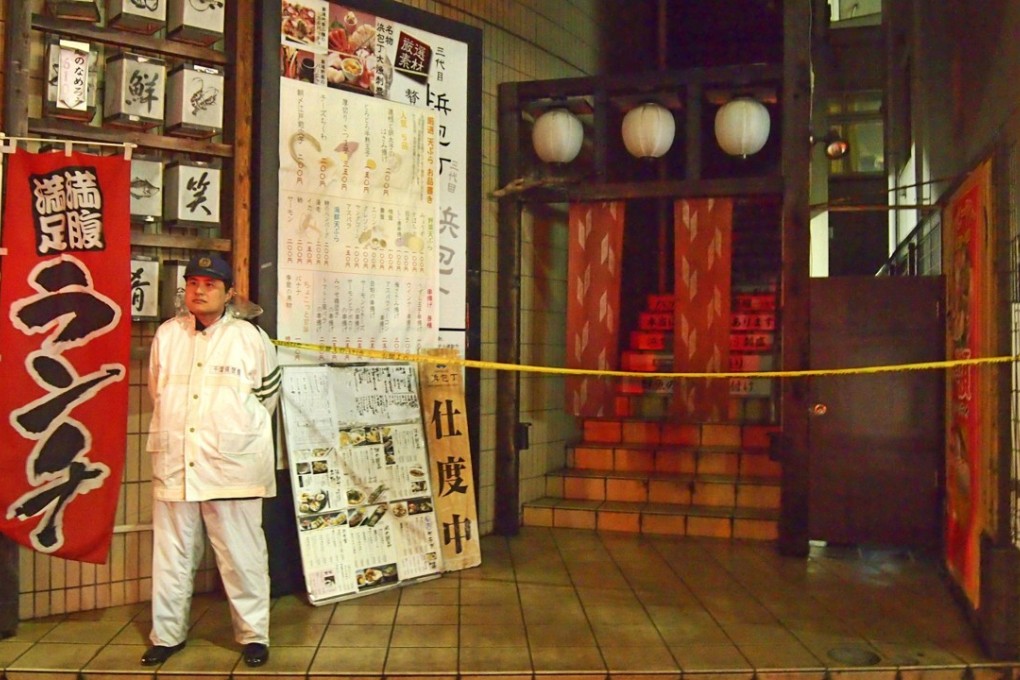 A police officer stands guard near a restaurant where four family members were stabbed by a man in Chiba, Japan, on Sunday. One of them, a girl, died. Photo: Kyodo