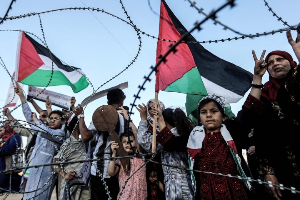 Children raise the Palestinian flag as one boy holds a wooden key symbolising the return, as they stand with others before the barbed wire marking the border between the Gaza strip and Israel, in the east of Gaza City on May 13. The demonstration came two days before marking 70 years since the Palestinian “nakba”, or catastrophe, of 1948, when over 700,000 Palestinians fled or were expelled from their homes in the 1948 war surrounding Israel’s creation. Photo: AFP