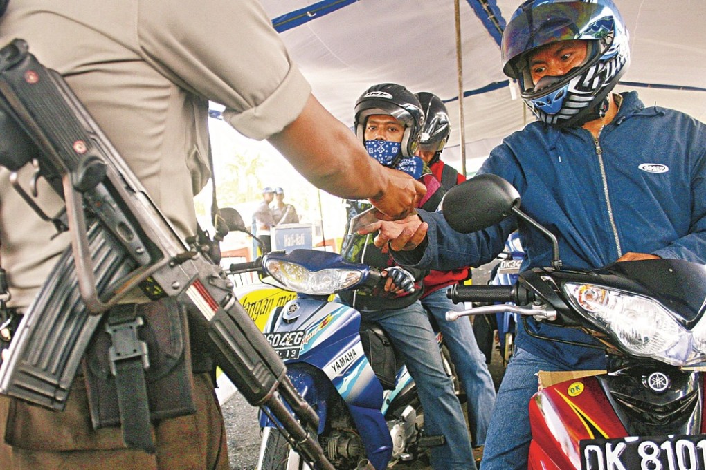 An armed policeman holds a security check to motorists at Bali’s Gilimanuk ferry port. Photo: AFP