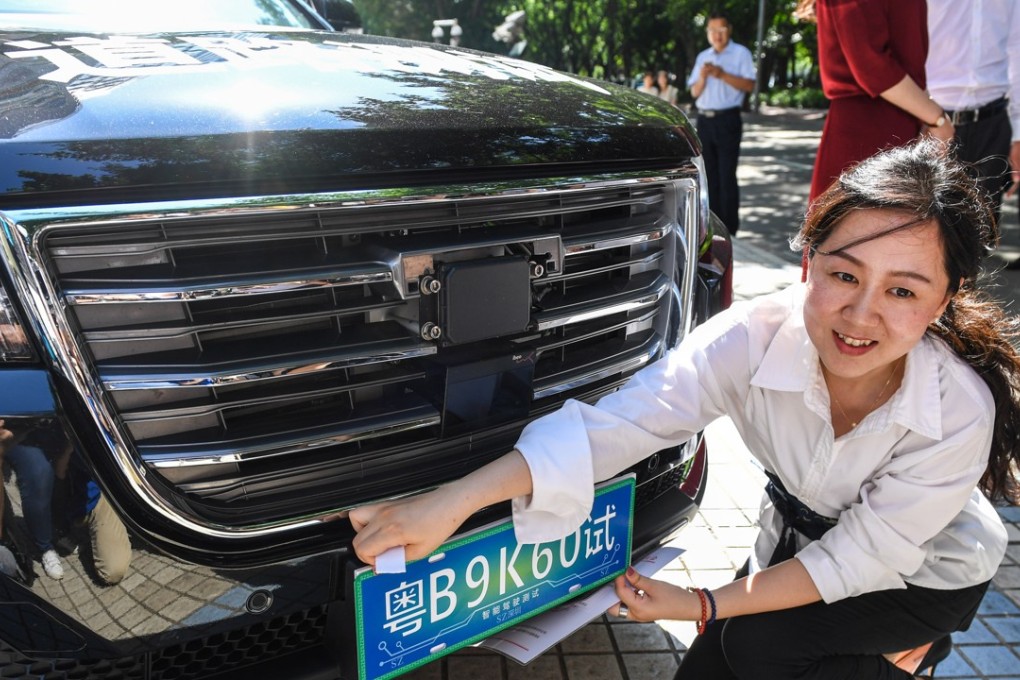 A staff member of Tencent Holdings installs a temporary license plate on a self-driving vehicle for road tests in Shenzhen. Tencent on Monday received a government permit to test its autonomous car on certain public roads in the southern coastal city. Photo: Xinhua