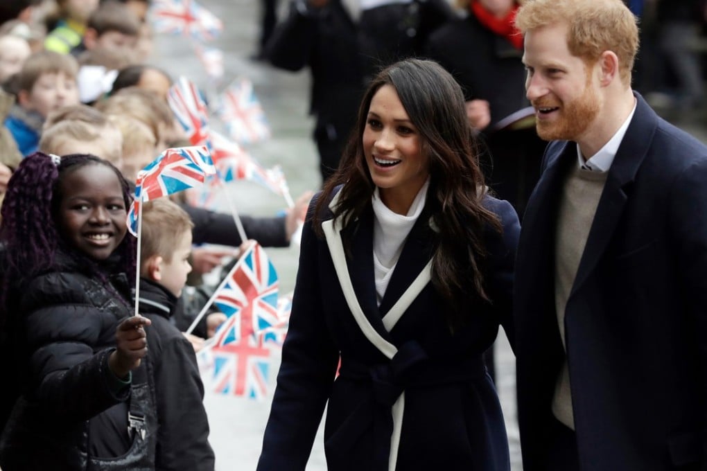 Prince Harry and Meghan Markle are greeted by flag-waving schoolchildren as they arrive to take part in an event on International Women's Day in Birmingham, England, on March 8. Photo: AP