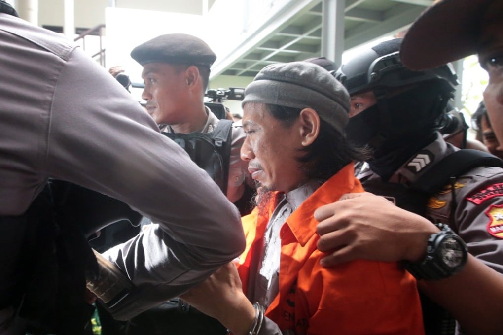 Suspected terrorist Aman Abdurrahman is escorted by police officers. Photo: EPA