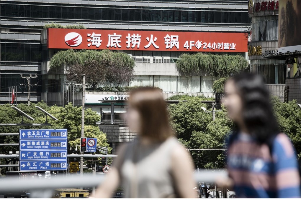 Pedestrians walk past a Haidilao hotpot restaurant, operating 24 hours of the day, in Shanghai. Photo: Bloomberg