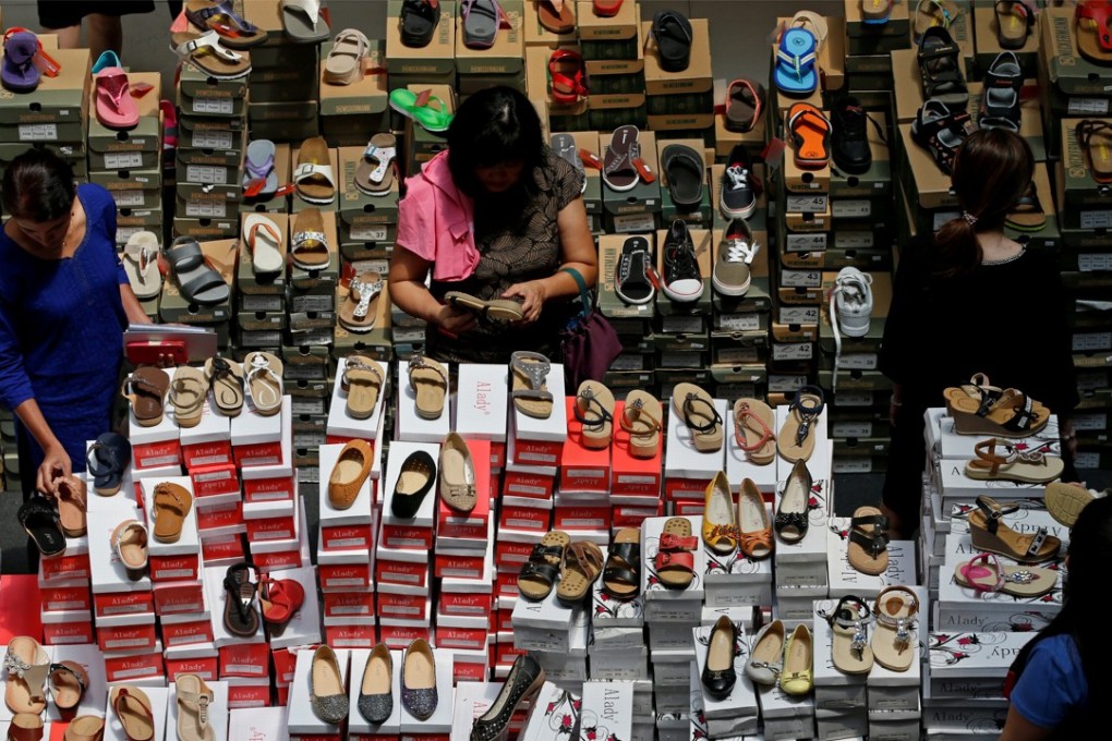 People shop for shoes at a mall in Singapore in May 2016. Online shopping has gained in popularity, but not brought down prices for every customer. Photo: Reuters