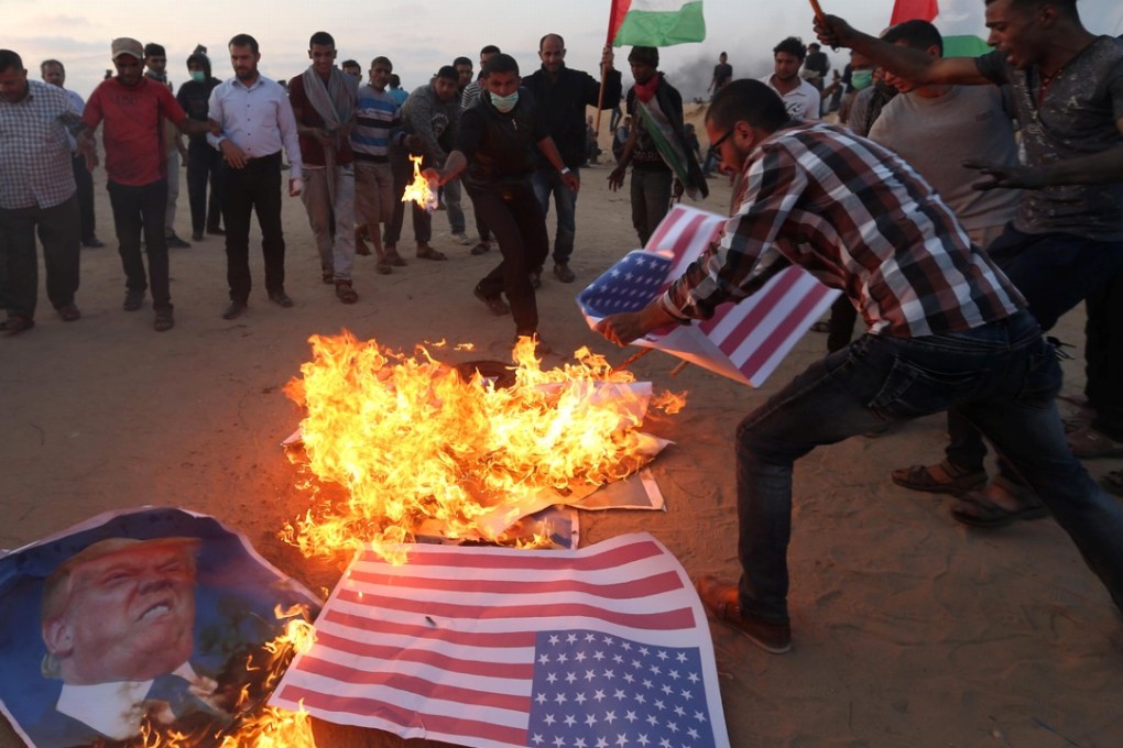 Palestinian demonstrators burn representations of US flags and a poster of US President Donald Trump during a protest marking the 70th anniversary of Nakba and against the US embassy move to Jerusalem, at the Israel-Gaza border in the southern Gaza Strip on Tuesday. Photo: Reuters