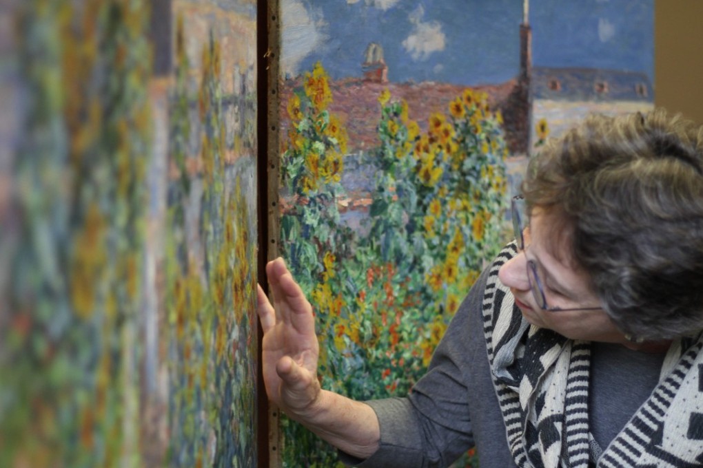 Ann Hoenigswald, senior conservator of paintings at the US National Gallery of Art, looks at “The Artist's Garden at Vetheuil” (1881) by Claude Monet, unframed, with a version held by the Norton Simon Museum in the background, at the National Gallery of Art's conservation laboratory in Washington. Photo: Agence France-Presse
