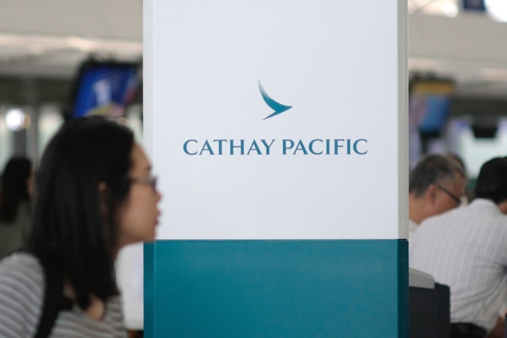 A traveller walks past a Cathay Pacific logo at Hong Kong International Airport. Photo: Fung Chang