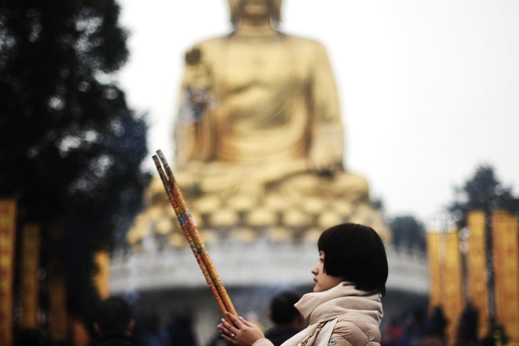 A woman offers a prayer in front of a large Buddha statue at Huayan Temple in Chongqing in this file photo. China’s Communist Party has ordered local governments to better regulate the construction of outdoor religious statues amid increasing restrictions on religious expression. Photo: AP
