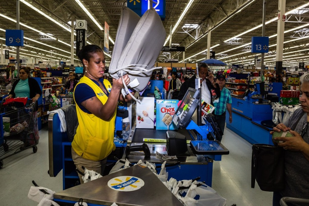 An employee scans a customer's purchases at a Walmart. An alliance of rights groups has released a report claiming that women who work in Asian factories making clothes for the global retail giant are at “daily risk” of slapping, sexual abuse and other harassment. Photo: Bloomberg