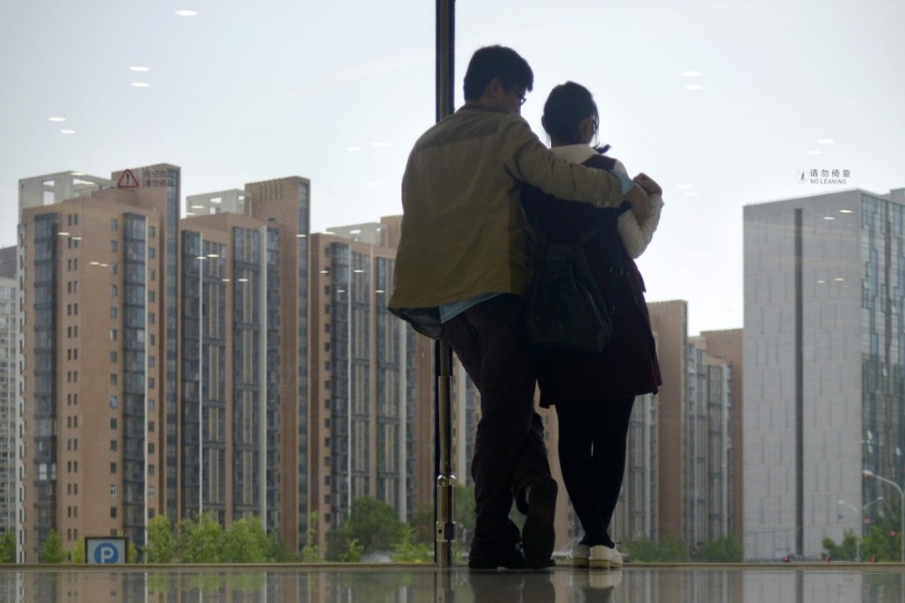 A young couple looks longingly out of the window of a shopping centre in Beijing, at flats they might never be able to afford to buy.Photo: AFP