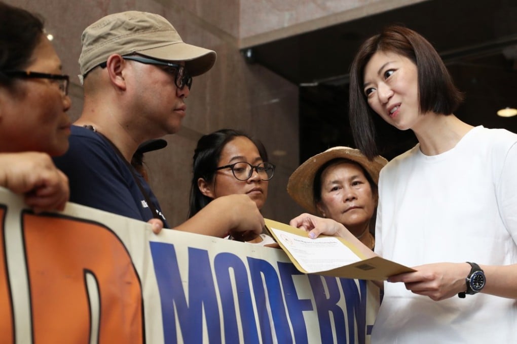 Yung (right) receives a letters from representative of the city’s domestic workers outside the New People’s Party’s headquarters in Wan Chai. Photo: Winson Wong