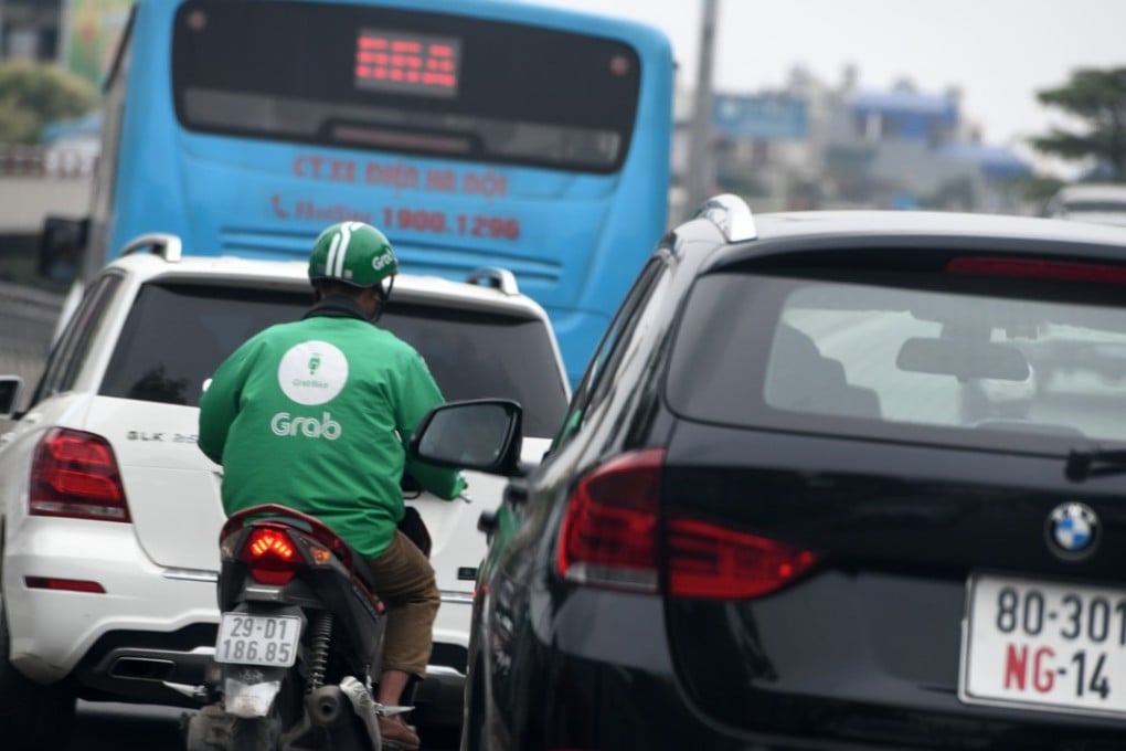 A Grab motorbike taxi rider plies between vehicles on the street in Hanoi, Vietnam, last month. Photo: AFP