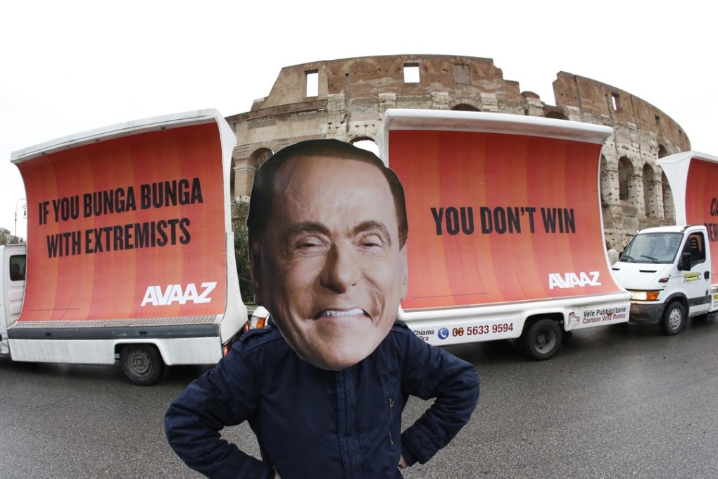 An actor wearing a mask depicting former Italian premier Silvio Berlusconi performs alongside three billboards in front of the colliseum in Rome after Italy’s election day in March. The billboards were in response to the right-wing coalition not winning a clear majority. Photo: AP/ Avaaz
