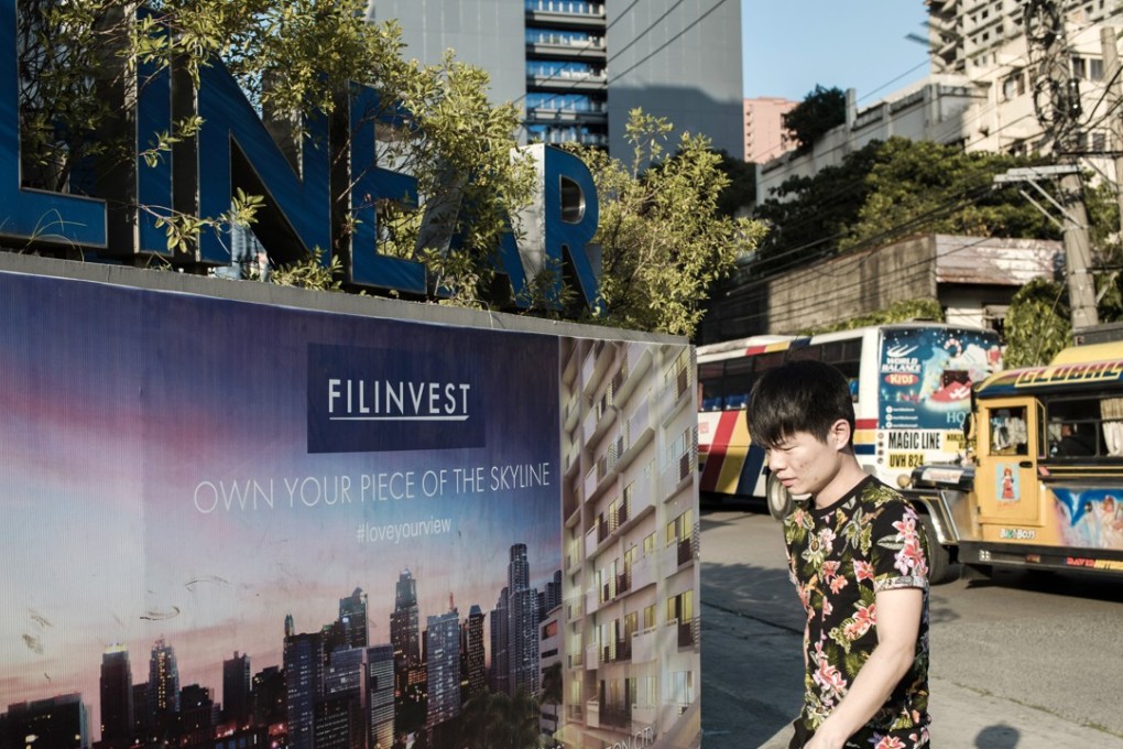 A pedestrian walks past signage advertising property investment in Makati City, Manila, the Philippines. Photo: Bloomberg