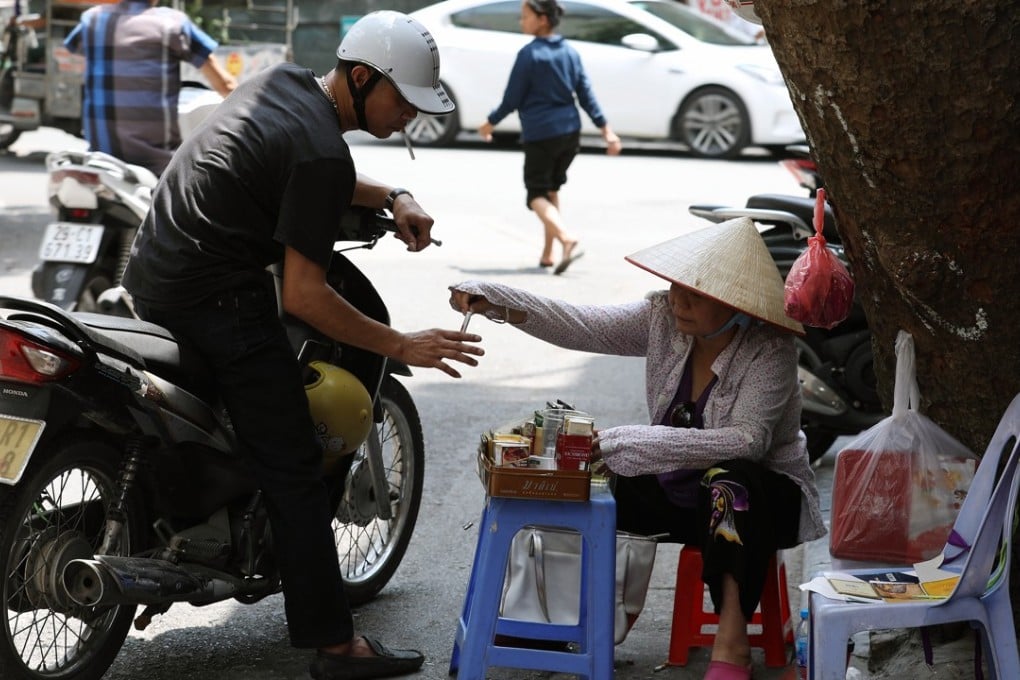 A woman sells cigarettes to a man on a street in Hanoi, Vietnam. Photo: EPA
