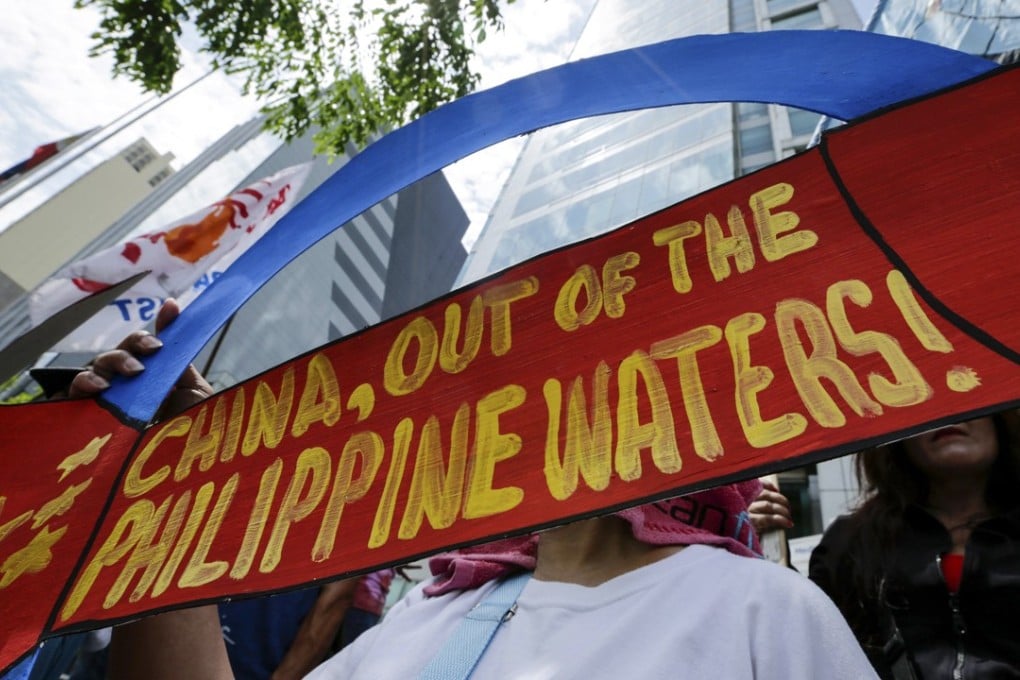 A woman holds a placard at the Chinese consulate in Makati on May 18 in a protest over Beijing’s installation of cruise and surface-to-air missiles on artificial islands in the Spratly group. Photo: EPA-EFE