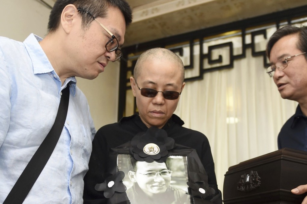 Liu Xia, the wife of Liu Xiaobo, holds a portrait of her husband at his funeral last year. She remains under de facto house arrest. Photo: AP