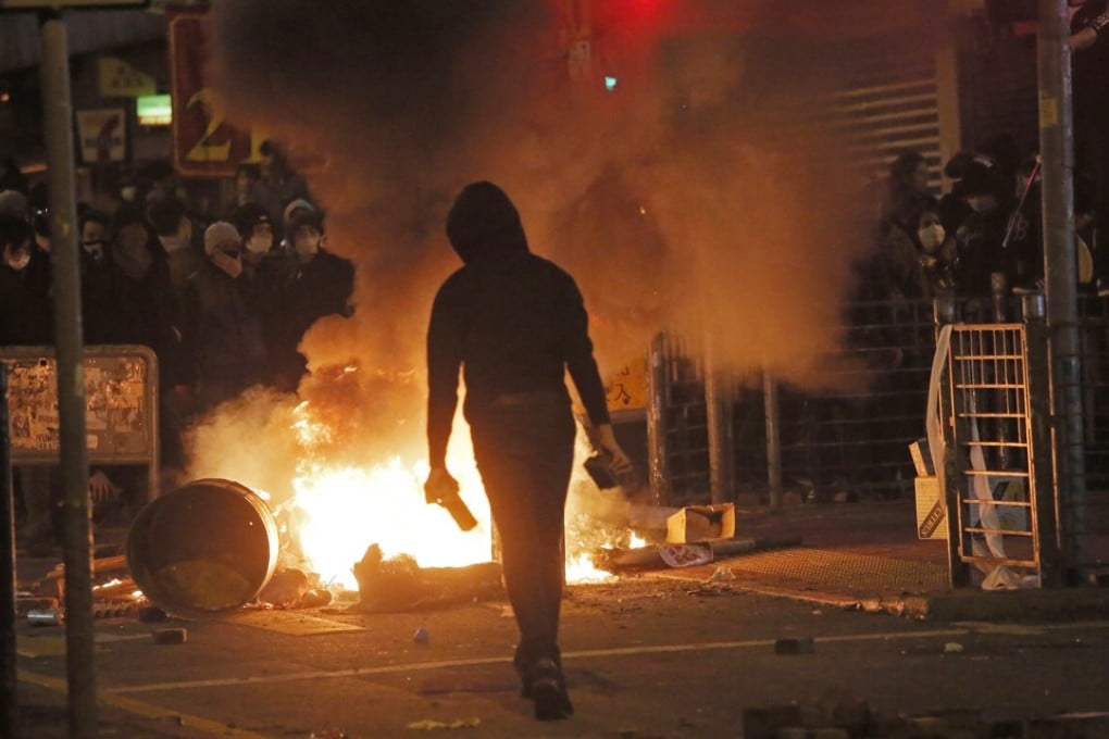 A rioter holds bricks in front of fires in Mong Kok on February 9, 2016. Hong Kong's Lunar New Year celebration descended into chaotic scenes as protesters and police clashed over a street market selling fish balls and other local holiday delicacies. Photo: AP