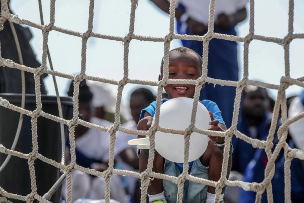 A child plays with a rubber glove on board the Spanish Navy 'Numancia' ship in Palermo, Italy. Photo: EPA