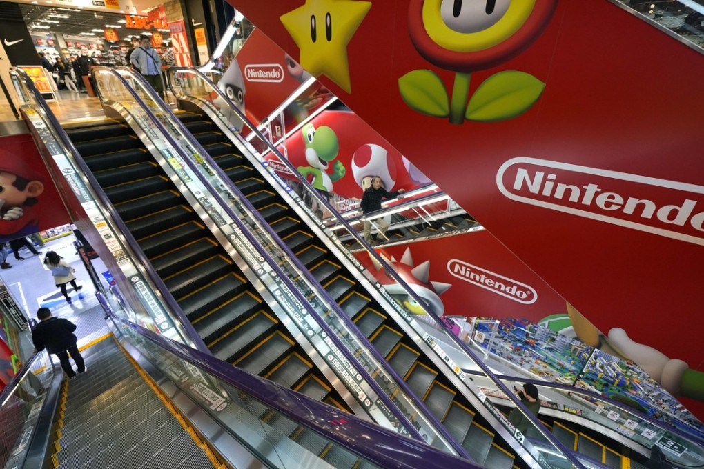 Shoppers standing on an escalator pass by the Nintendo logo at an electronics store in Tokyo. Photo: AP