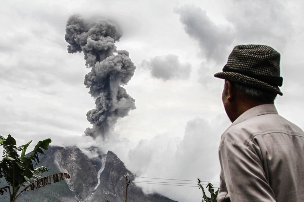 An Indonesian man watches as Mount Sinabung spews thick smoke in Karo, North Sumatra on January 4. The Indonesian central bank is fighting fire as the strengthening dollar and rising oil prices have put pressure on the country’s economy. Photo: AFP