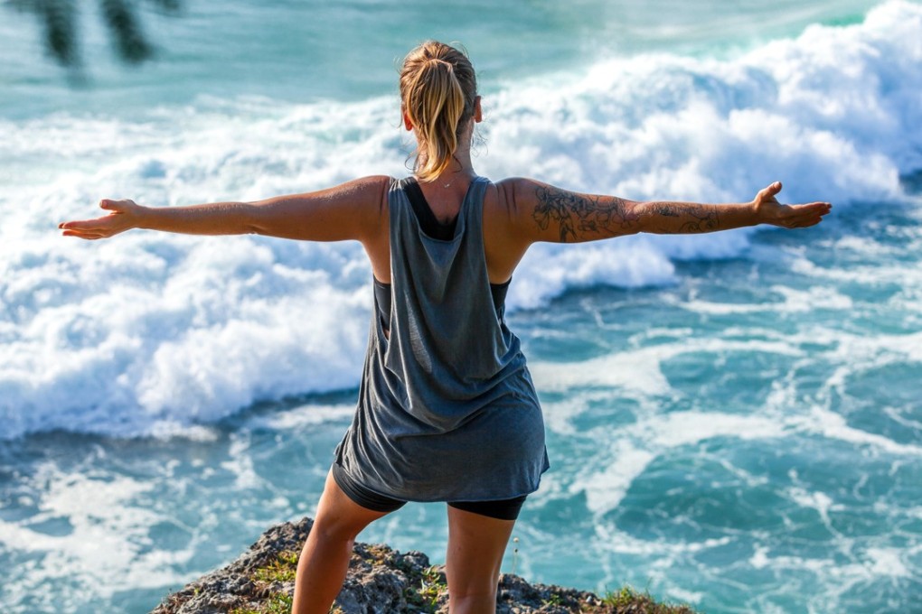 A female traveller looks out over the crystal clear blue water of the Indian ocean at Uluwatu beach, Bali, in Indonesia. Photo: Alamy