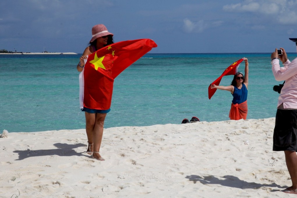Tourists take souvenir photos with a Chinese flag as they visit Quanfu island, one of Paracel Islands of China's Hainan province in the South China Sea in 2014. Photo: AP
