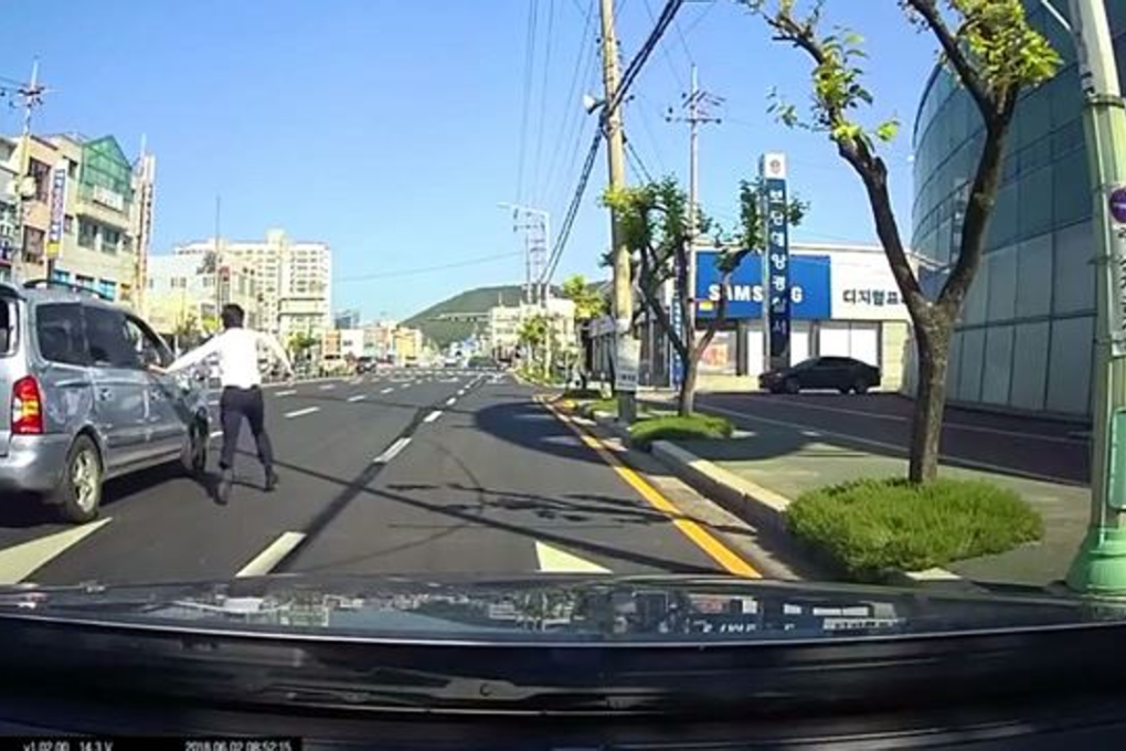 Kia Motors salesman Son Ho-jin attempts to rescue a driver who had been in an accident in an intersection in Boryeong, South Chungcheong Province, Saturday. Photo: Son Ho-jin